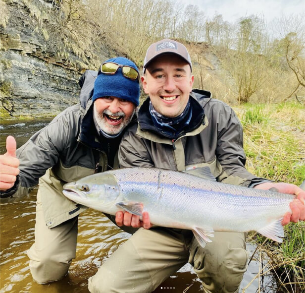 Two smiling anglers with their fish showing thumbs up