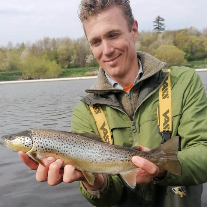 Hendrik in the river holding a small brown trout