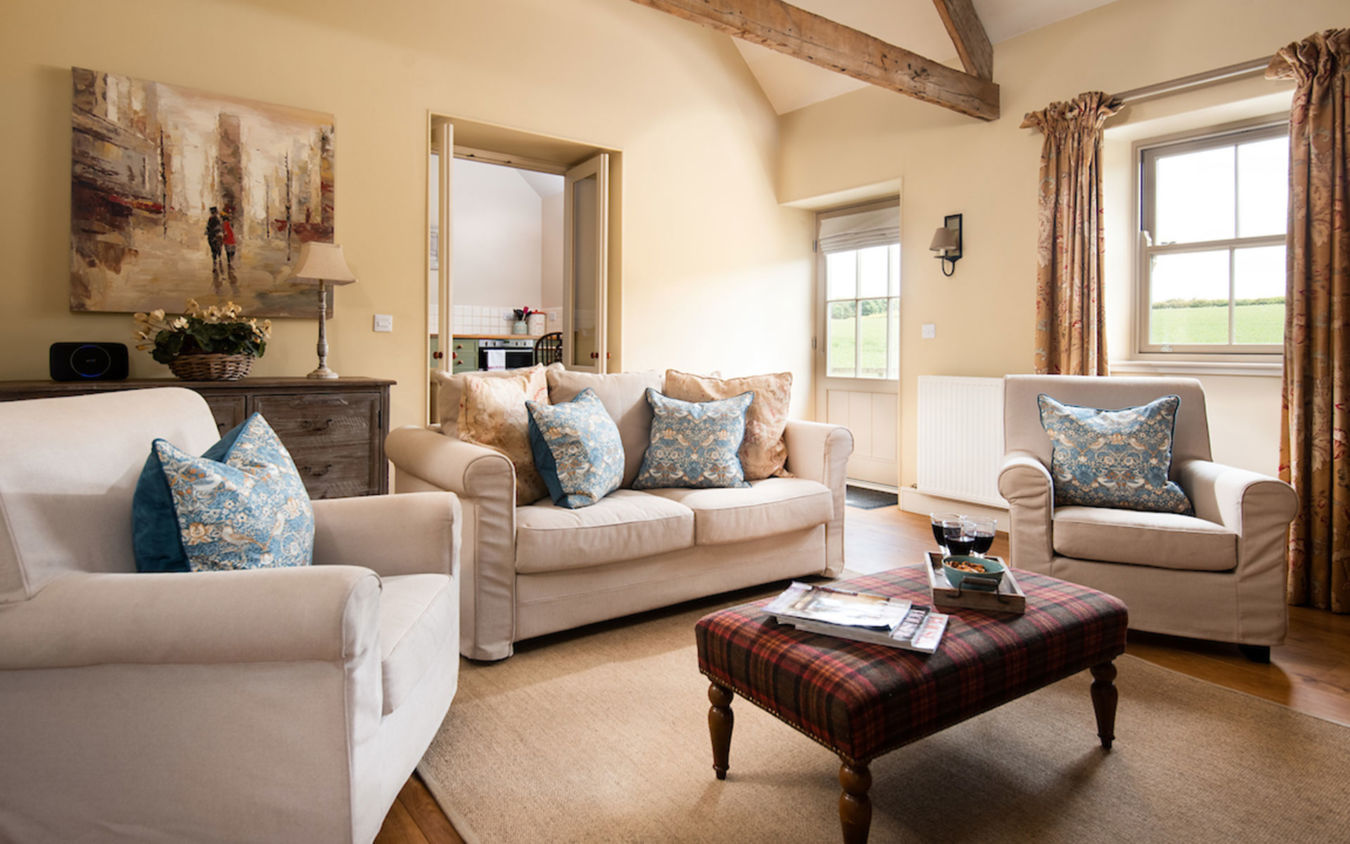 Living room layout in The Smithy with comfy sofa and chairs and tartan stool